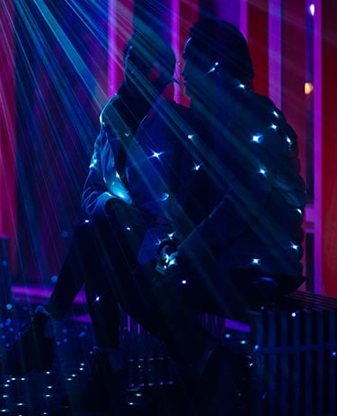 Two people sitting in purple light at Nightrise.