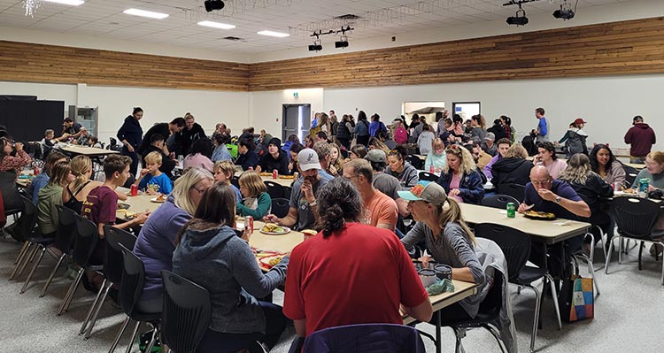 A community dinner with lots of people in a banquet hall.