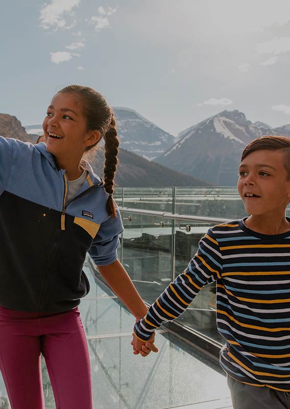 Two children walk on the Columbia Icefield Skywalk in the summer.