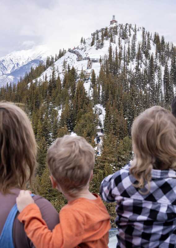 A family looking at the view of Sanson's Peak from the Banff Gondola summit.
