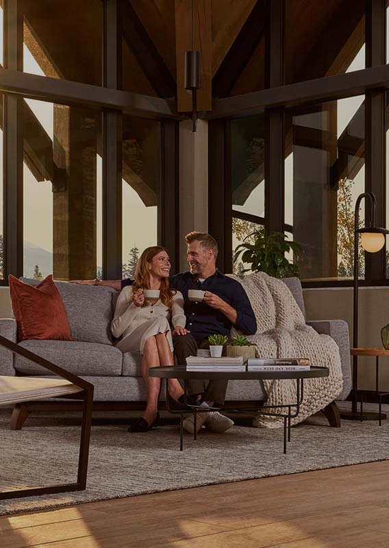 Two people sit in a leather sofa in a rustic-modern hotel lobby