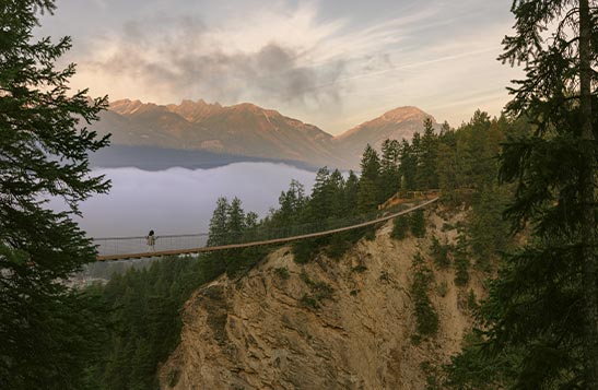 A narrow suspension bridge across a wide canyon.