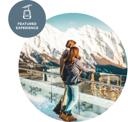 A couple look out at the top of Banff Gondola in winter.