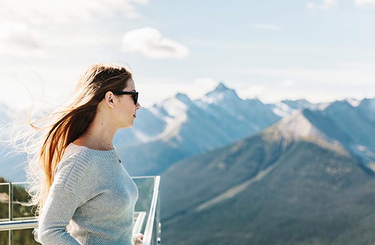 Two friends sit together at an outdoor fireplace atop a mountaintop observation deck.