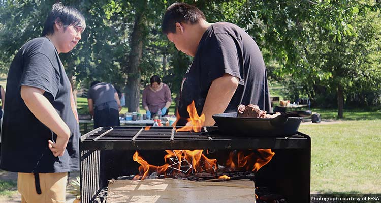 Young cooks prepare a meal outdoors in a park with an open fire stove.