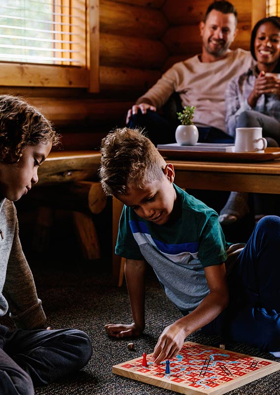 Kids playing checkers with parent relaxing in a mountain cabin