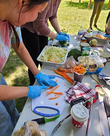 Cooks prepare food outdoors.
