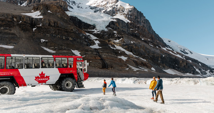 A family walking towards the Ice Explorer vehicle on the Athabasca Glacier at the Columbia Icefield.
