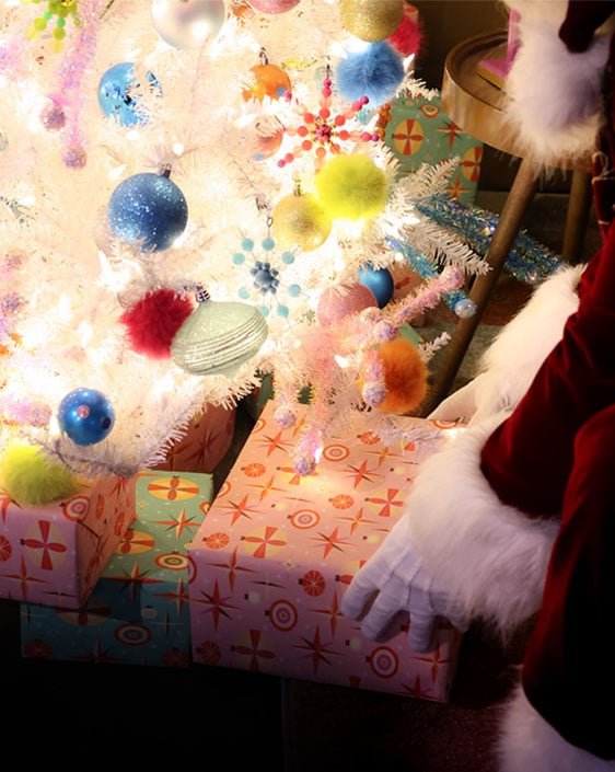 Santa placing a present under a Christmas tree