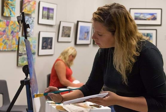 An artist painting at an easel.